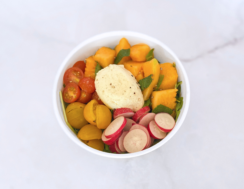 Une belle salade fraîche pour l'été faite de roquette, de melon, de menthe fraîche, de tomates cerises, de radis rouge et de mozzarella.