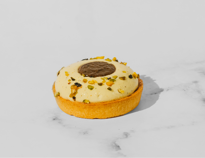 Pâtisserie faite d'une pâte sablée garnie d'un Trocadéro pistache, sous une ganache pistache au centre de laquelle se tient un fondant praliné.