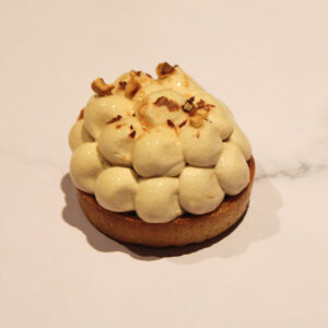 Sous sa pâte délicieusement croustillante se cache une crème fondante à la noisette, travaillée avec du praliné, du chocolat blanc et de fins éclats de noisettes pour une intensité irrésistible. Les crêpes dentelles ajoutent une touche de croquant raffiné, tandis que le nappage apporte une brillance subtile.